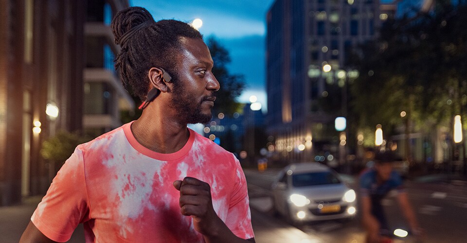 Sportaš koji koristi slušalice s prijenosom zvuka preko kosti na prometnoj ulici