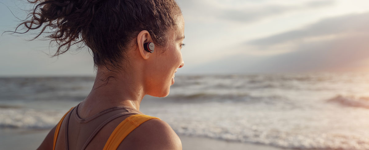 Žena uživa s Philips sportskim slušalicama na plaži