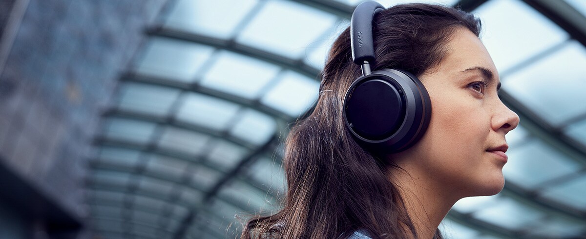 Žena uživa u glazbi na putovanju koristeći Philips L4 slušalice