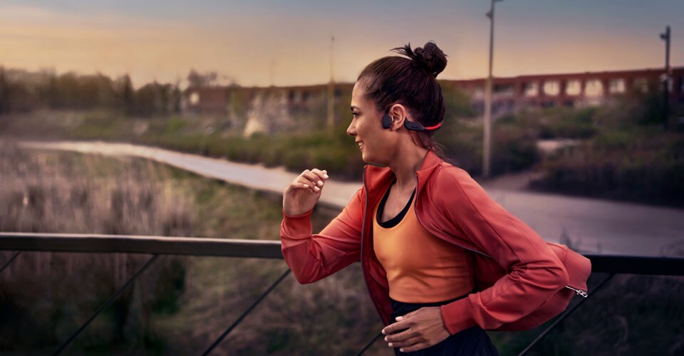 Sportaš koristi slušalice s prijenosom zvuka preko kosti dok trči vani