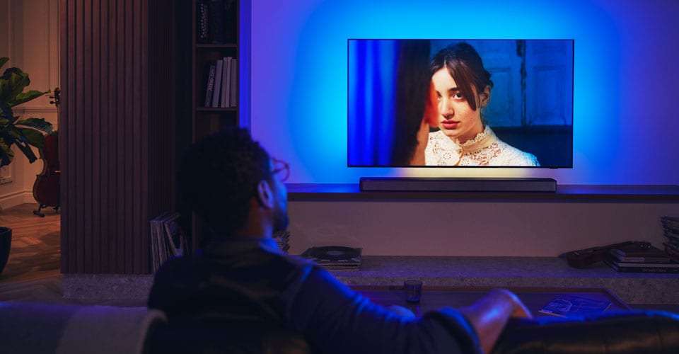 Čovjek uživa u Philips Ambilight TV-u sa soundbarom