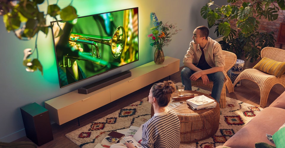 Ljudi koji uživaju u Philips Ambilight TV-u s jasnim soundbar zvukom