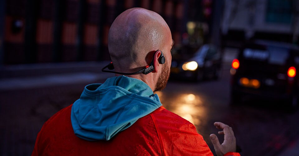 čovjek koji nosi slušalice s otvorenim ušima na prepunoj ulici