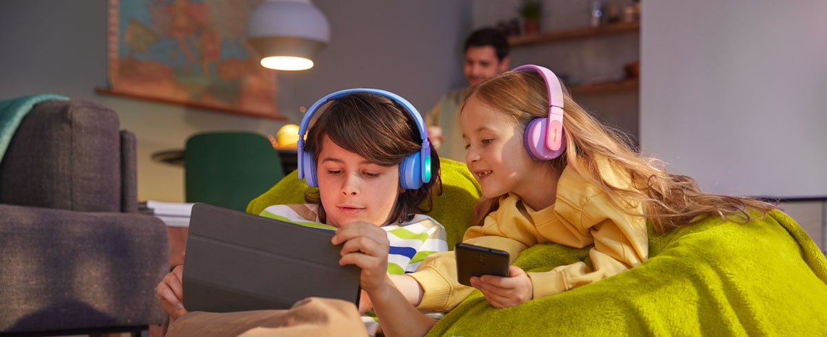 Dječak i djevojčica koriste svoje uređaje dok koriste izdržljive dječje slušalice