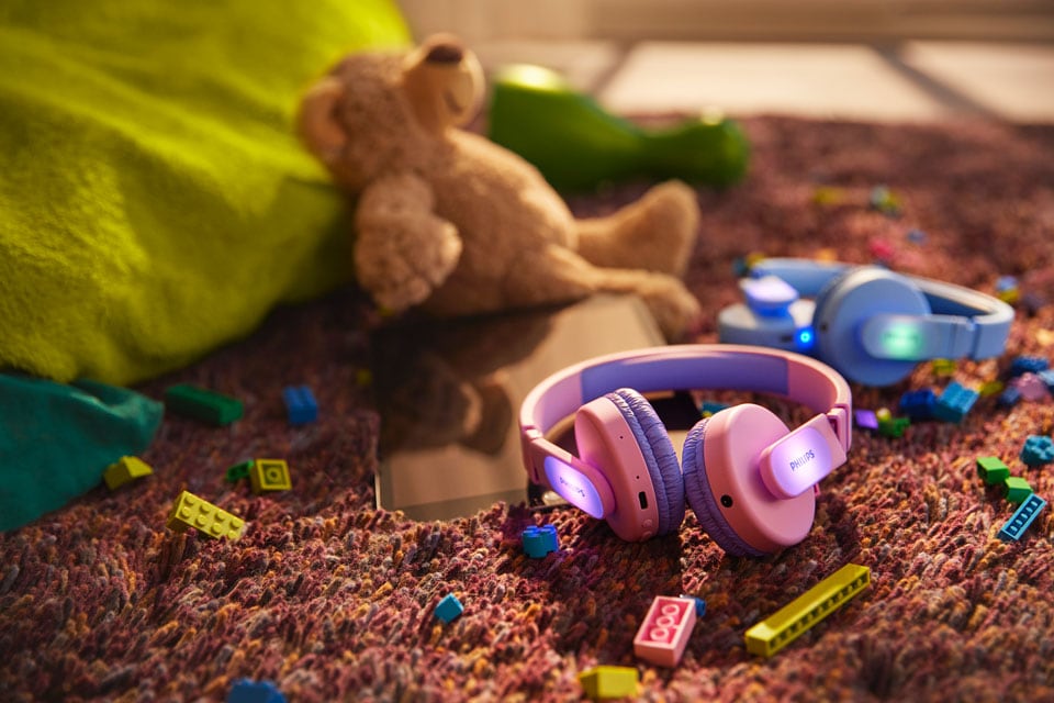Plave i ružičaste dječje slušalice na podu s igračkama