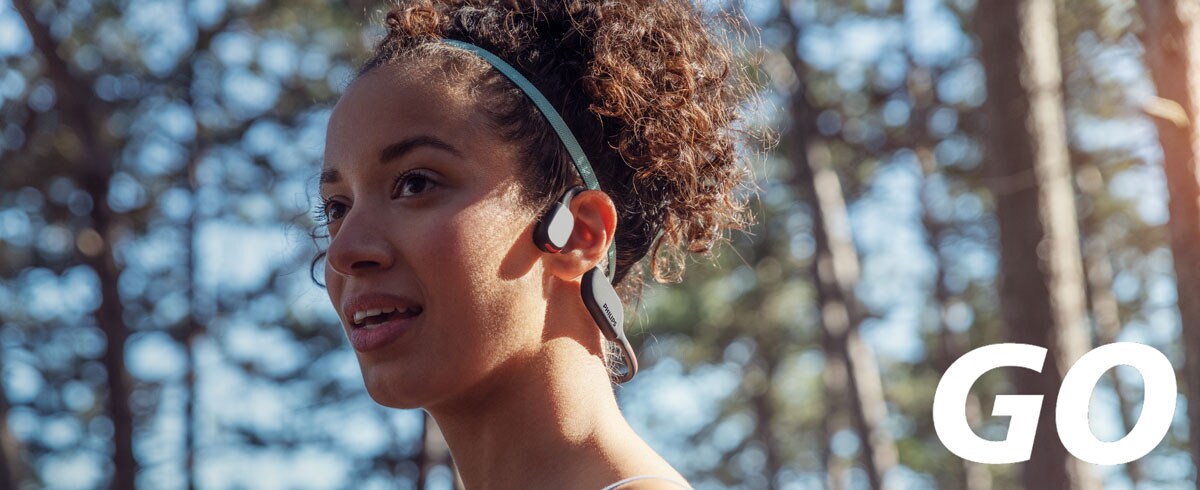 Krupni plan žene koja nosi sportske slušalice koje zvuk prenose preko kostiju