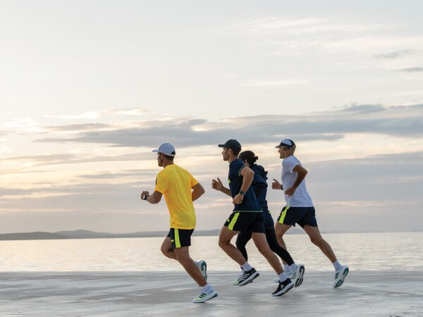 Četiri sudionika utrke zajedno trče na plaži.