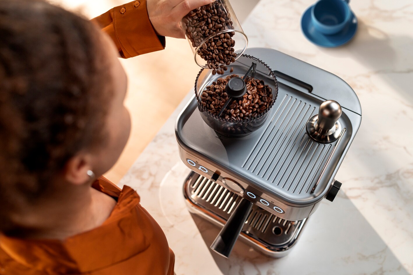 Mlada djevojka istresa zrna kave u spremnik za zrna kave aparata Philips Barista Brew